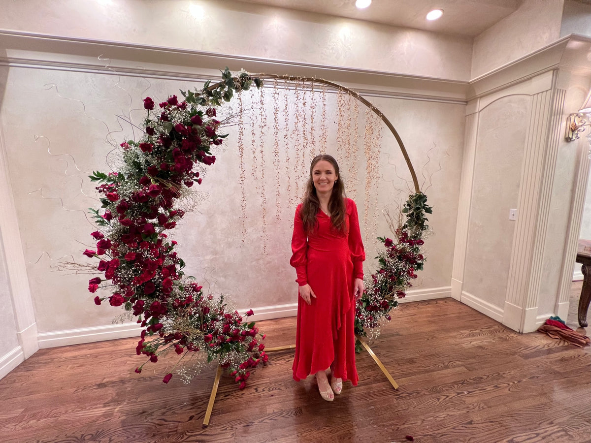 Circular wedding arch backdrop with deep red roses and greenery
