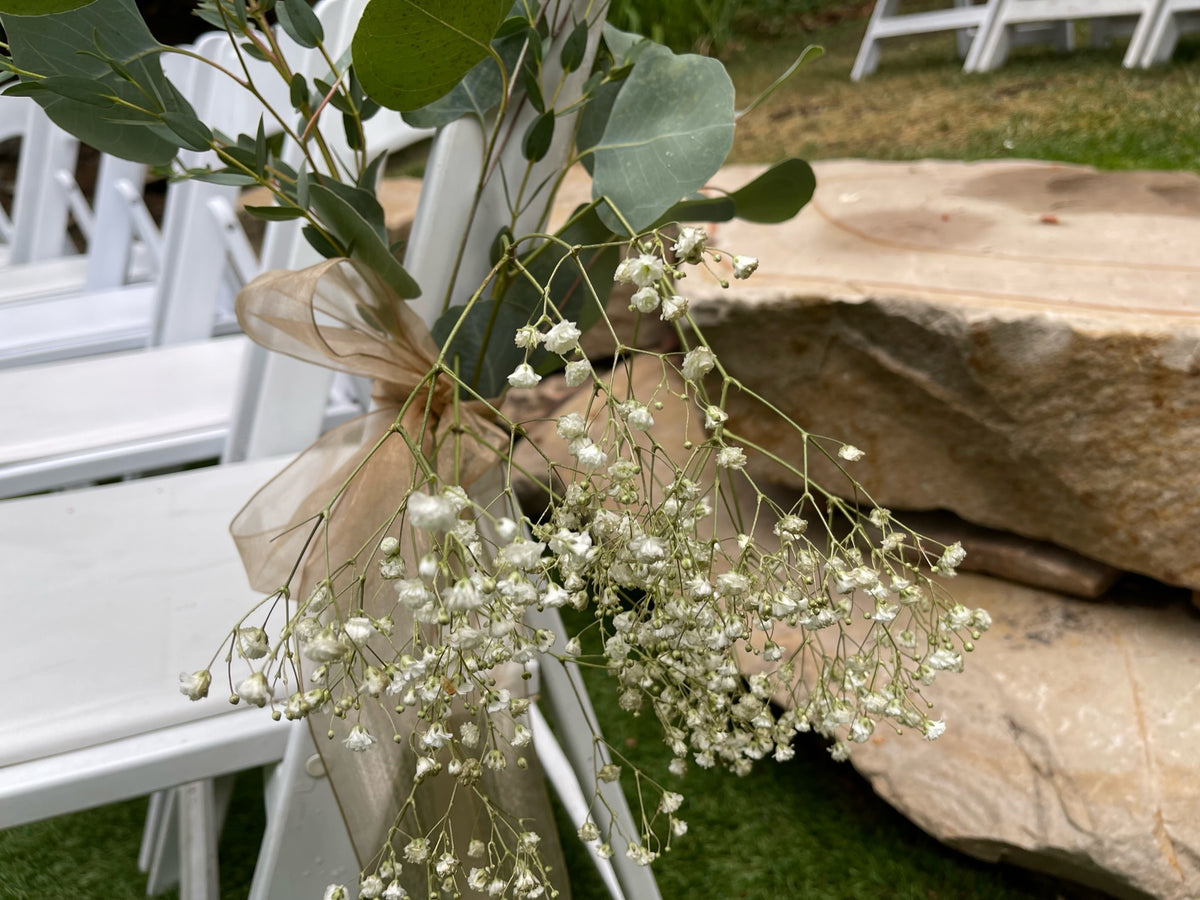 Wedding aisle chair decorated with baby's breath, eucalyptus and ribbon